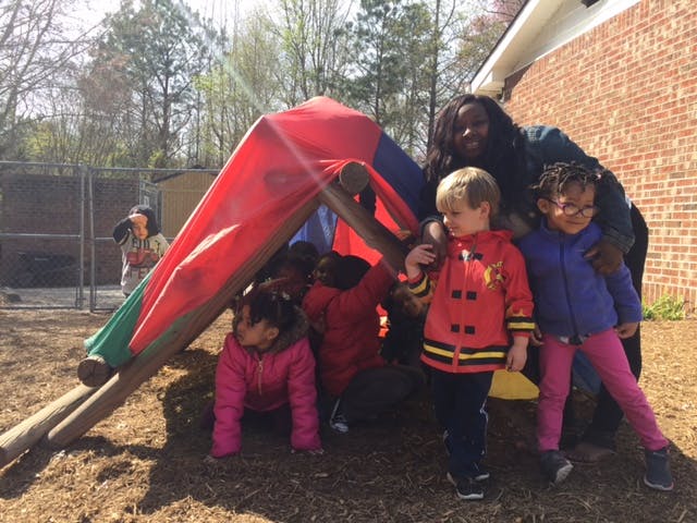 Adult and children playing on a colorful outdoor structure