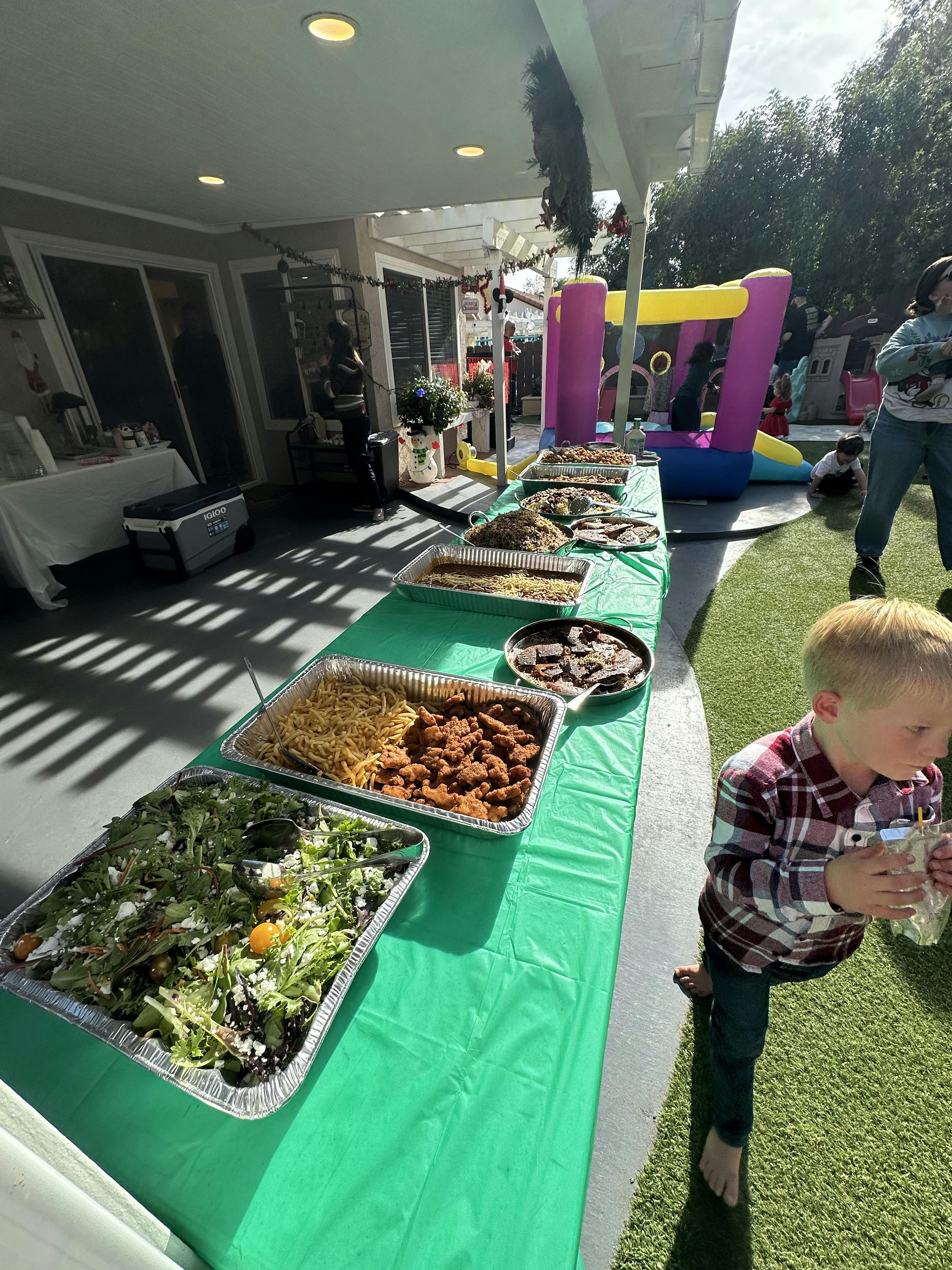Child standing next to a long table with food trays