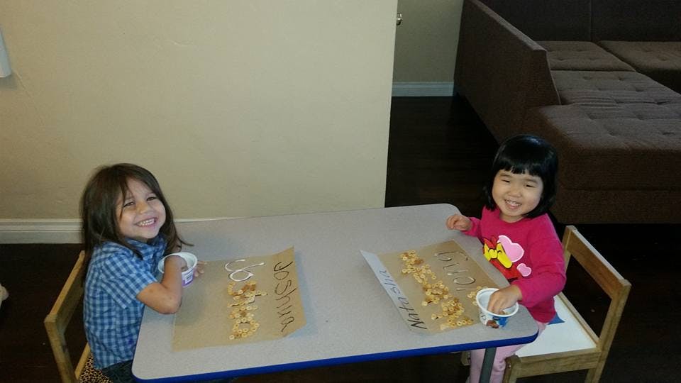 Two children sitting at a table with snacks