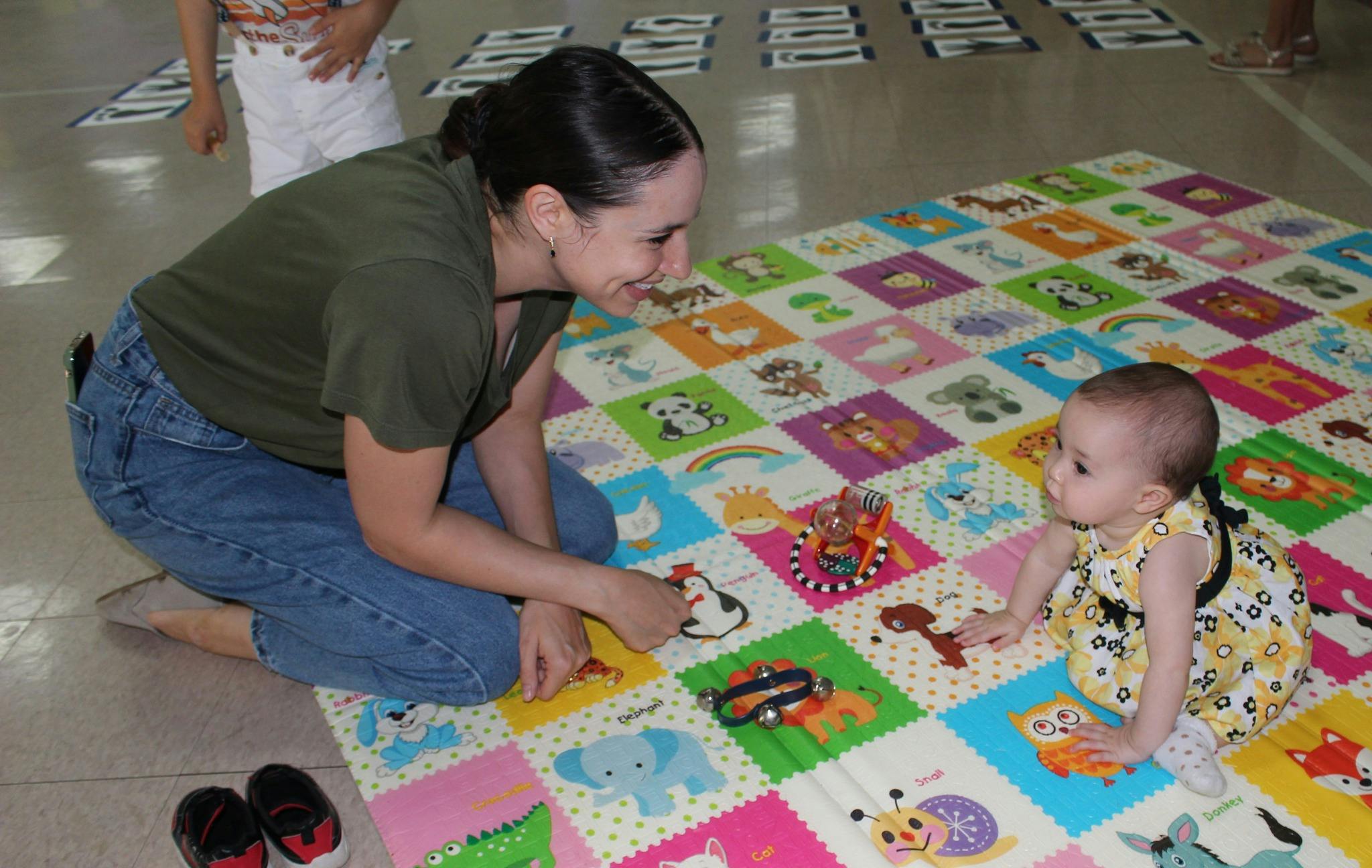 Person kneeling on playmat with infant