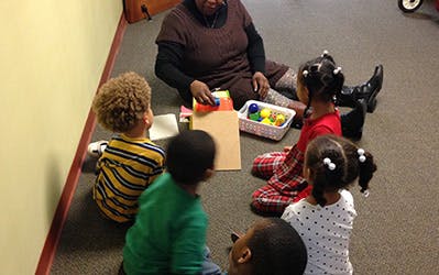 Adult and children sitting on floor playing with toys