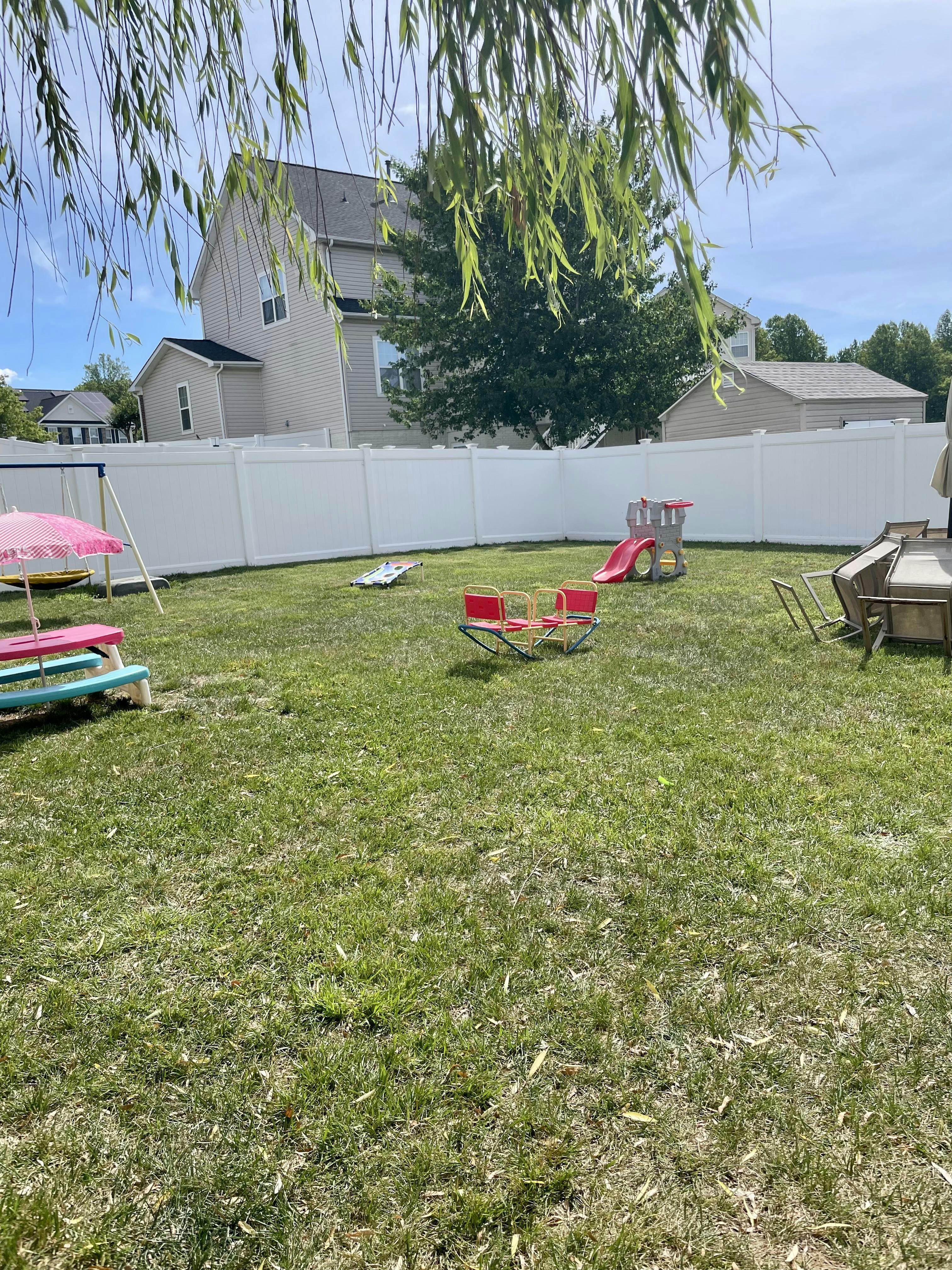 Backyard with play equipment including a small slide, seesaw, and picnic table