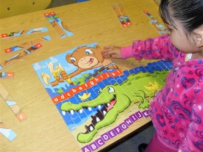 Child playing with an alphabet puzzle featuring a bear and an alligator