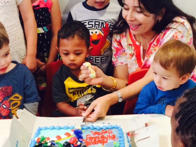 Person cutting a cake with children watching
