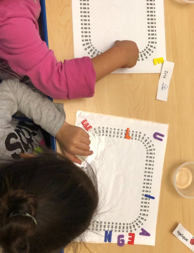 Two children working on letter and shape activities at a table