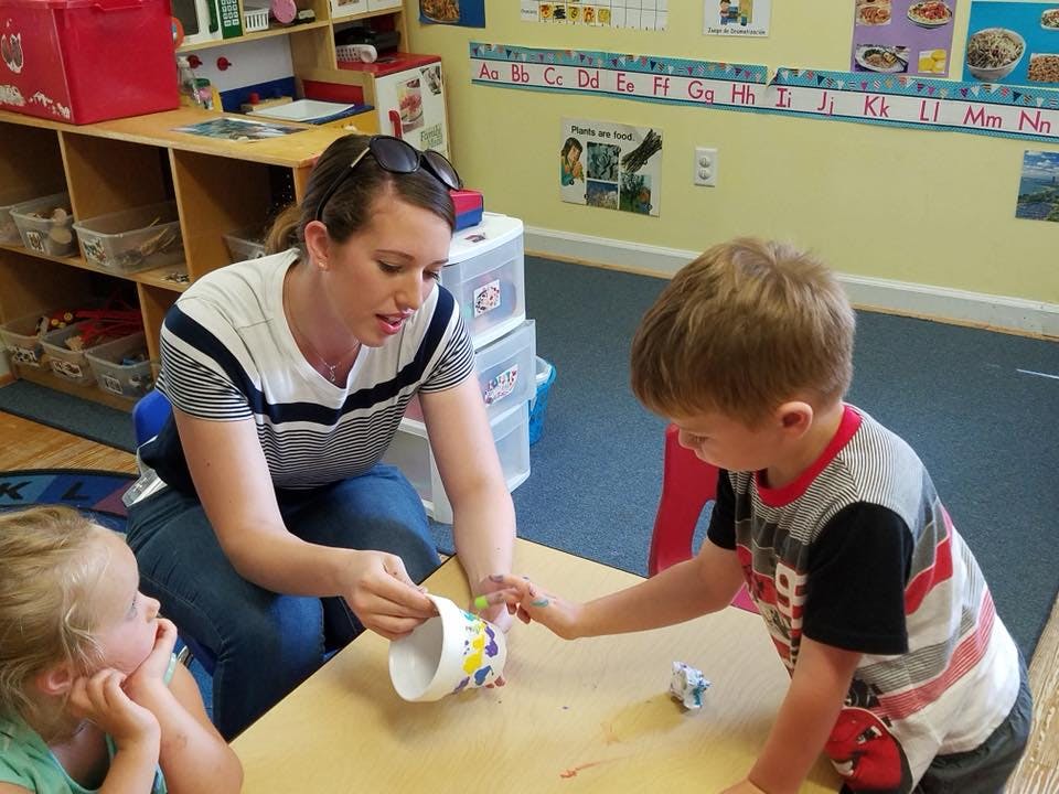Person and two children at a table in a classroom