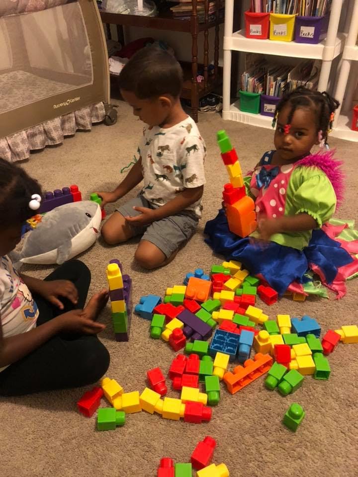 Three children playing with colorful building blocks on the floor
