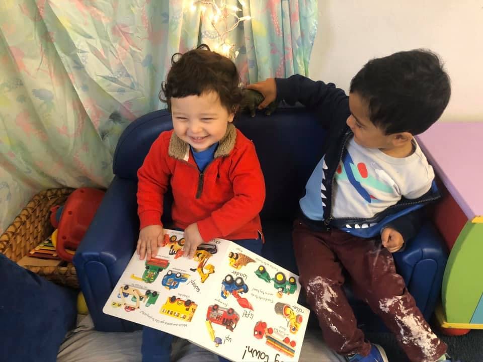 Two children playing with a puzzle on a blue chair