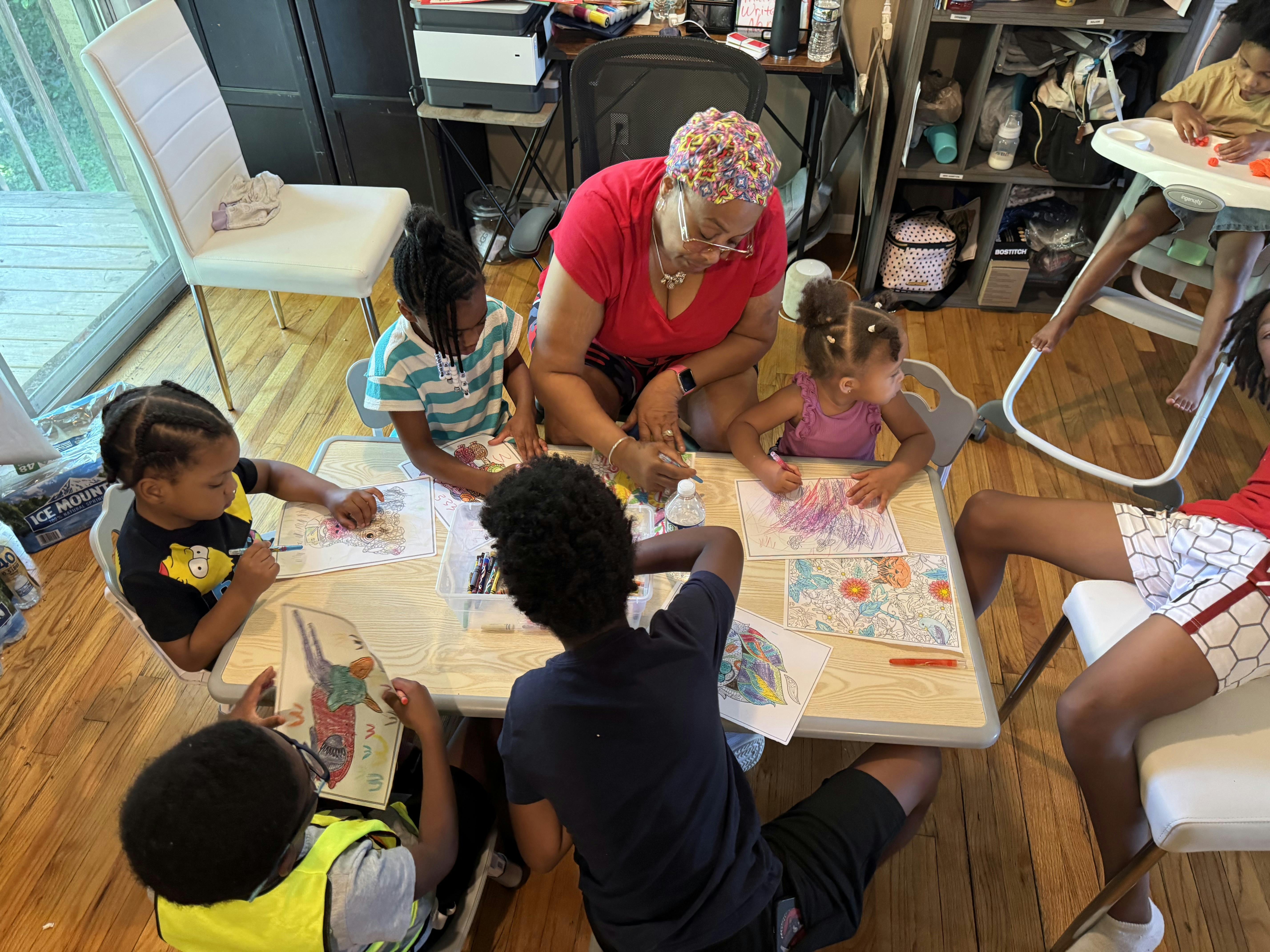 An adult and several children coloring at a table