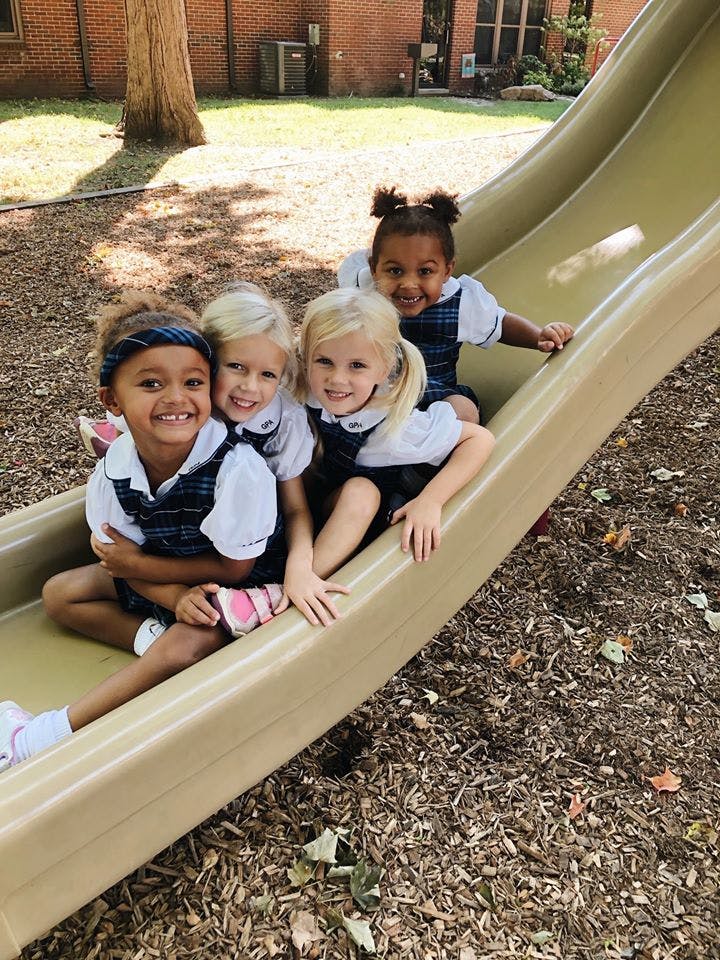Four children sitting on a playground slide