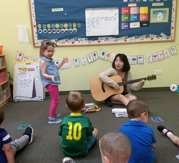 Person playing guitar for children in a classroom
