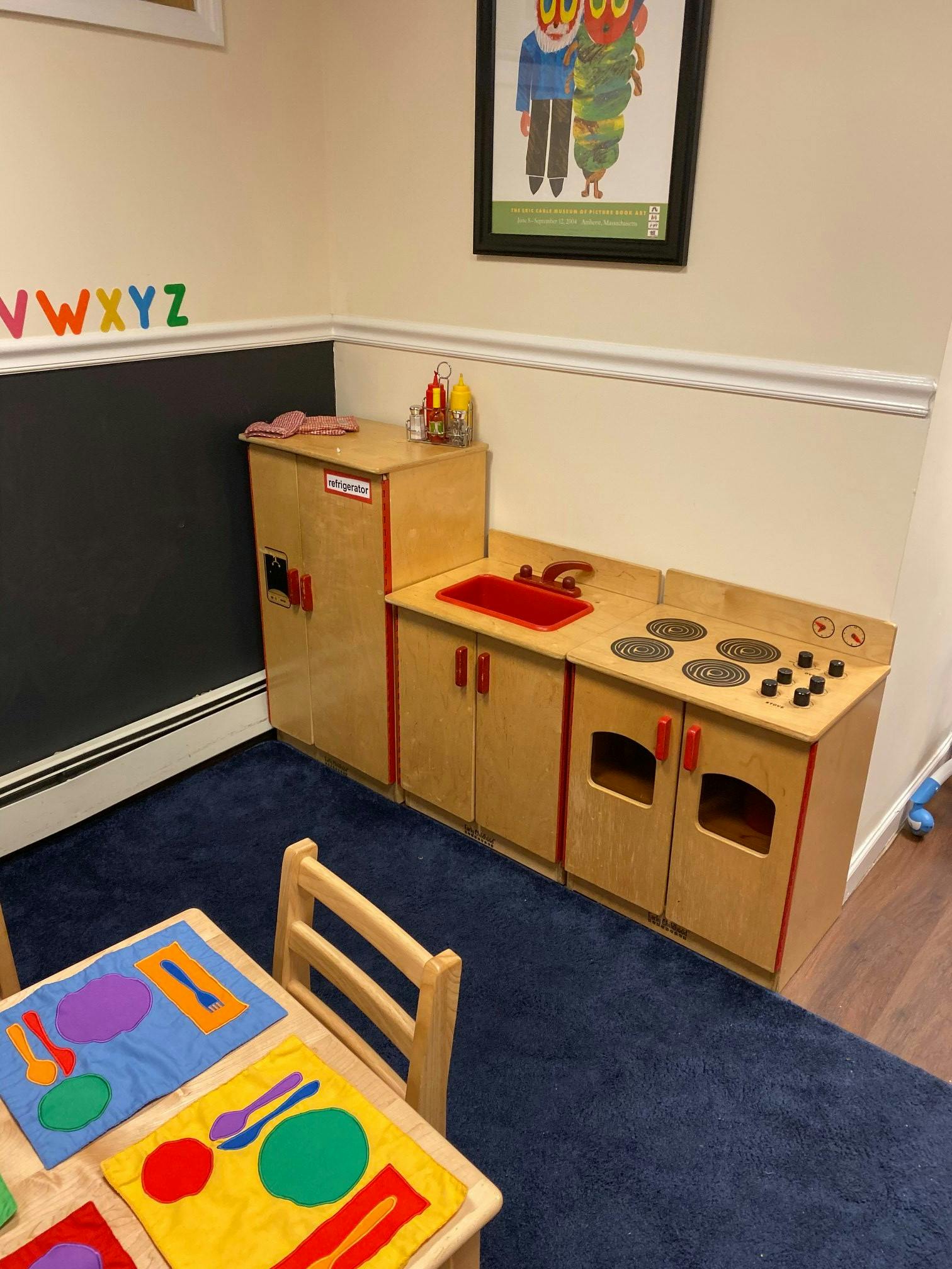 Play kitchen set with a refrigerator, sink, and stove in a classroom