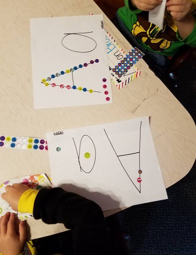 Children's hands next to papers with drawings and colorful stickers