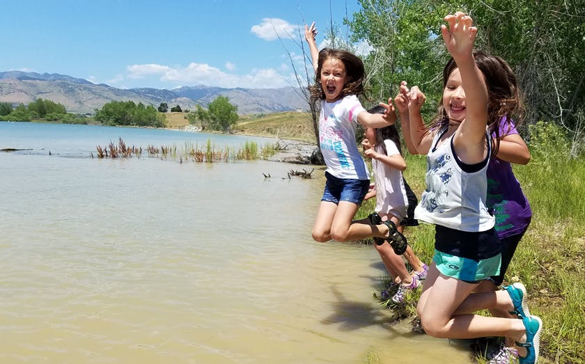 Children jumping in the air near a lake