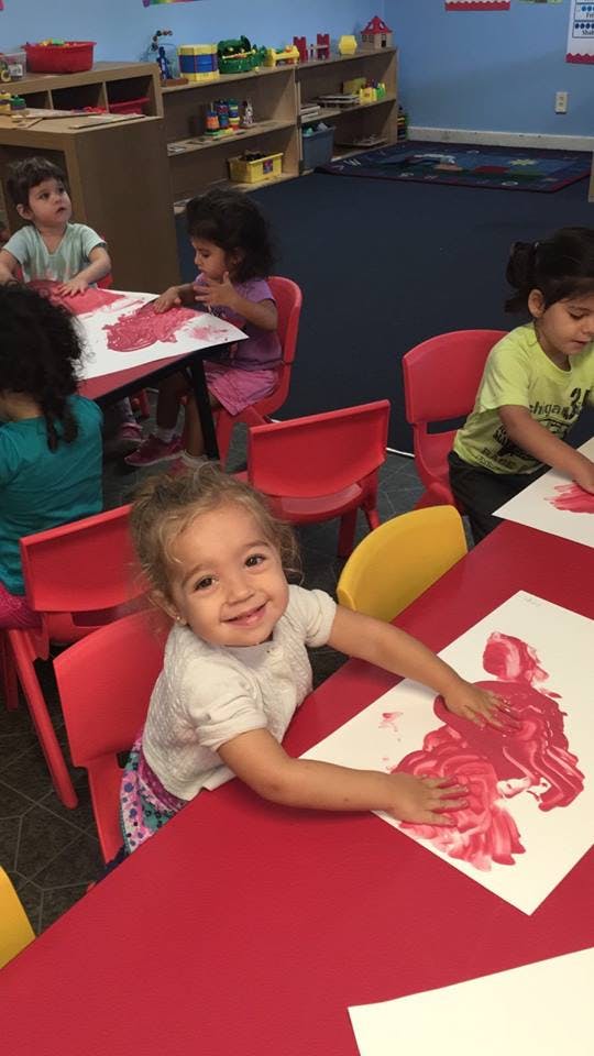 Child finger painting at a table in a classroom
