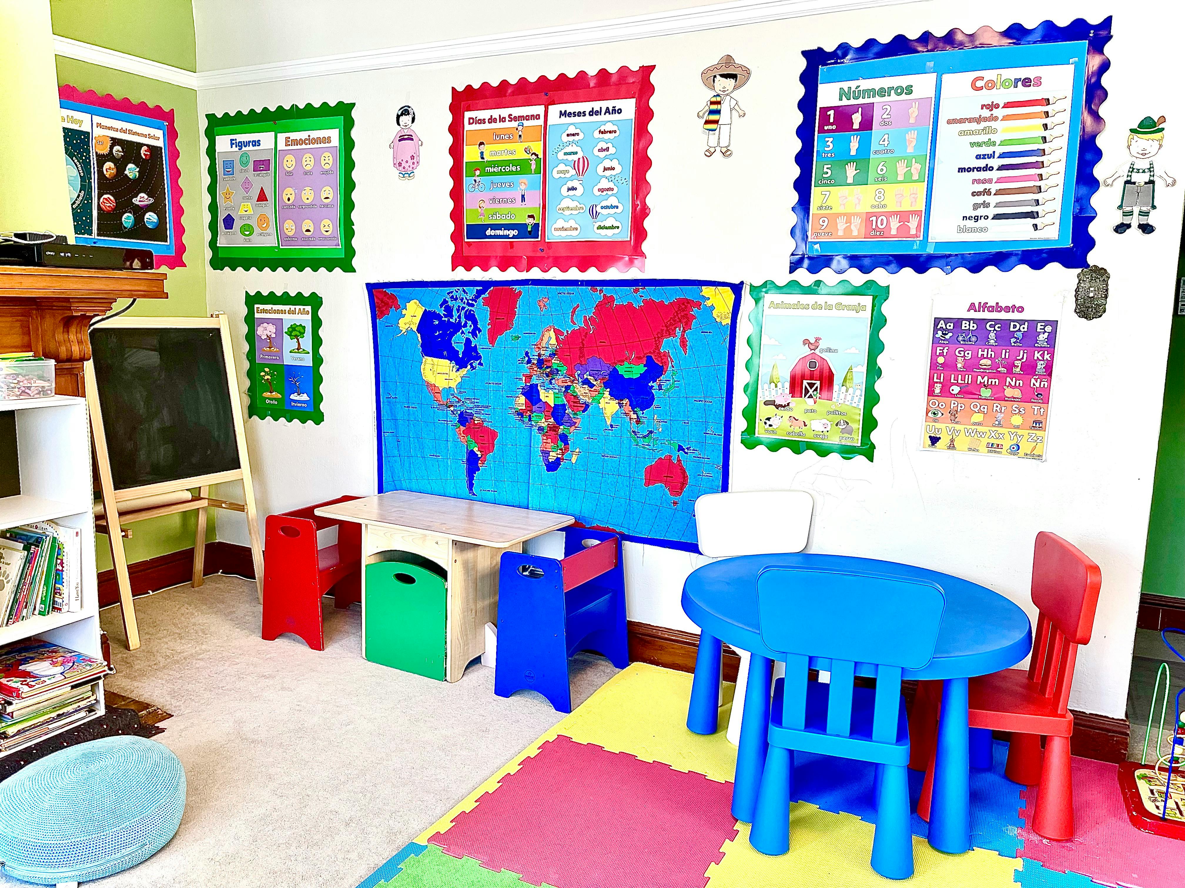 Classroom with colorful children's tables and chairs, world map, and educational posters