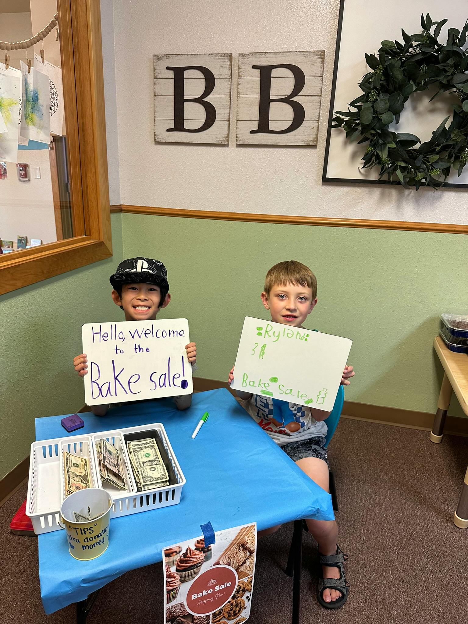 Two children holding signs for a bake sale
