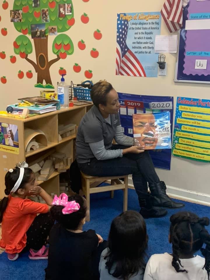 Adult reading a book to children in a classroom