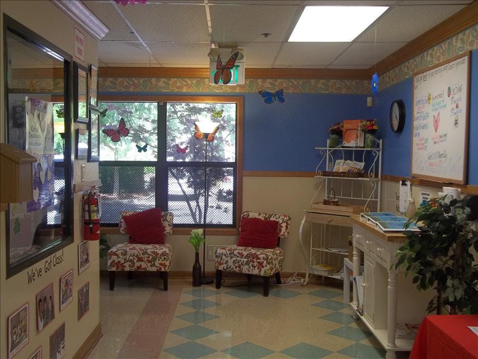 Waiting area with two floral chairs, a window with butterfly decorations, and a whiteboard
