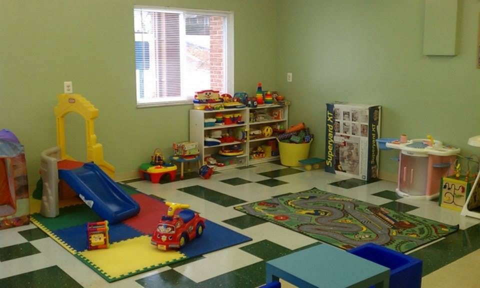Playroom with a small slide, toy shelves, and play mats