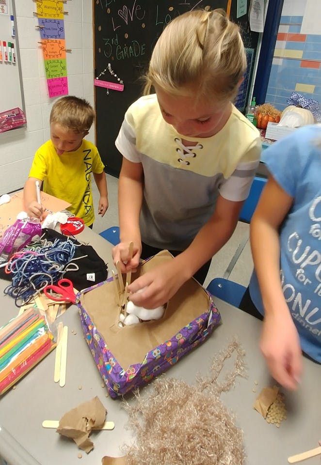Child working on a craft project at a table with another child