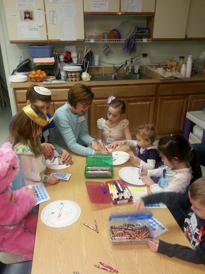 Adult and children doing crafts at a table in a kitchen