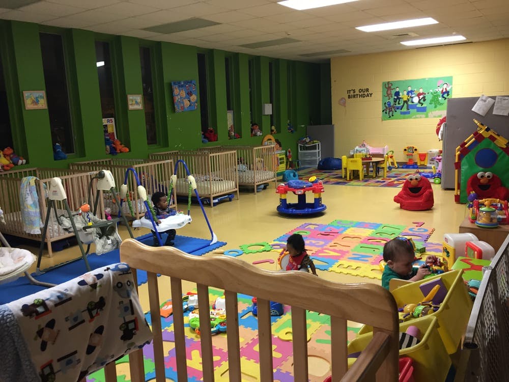 Children playing in a daycare room with cribs and colorful mats