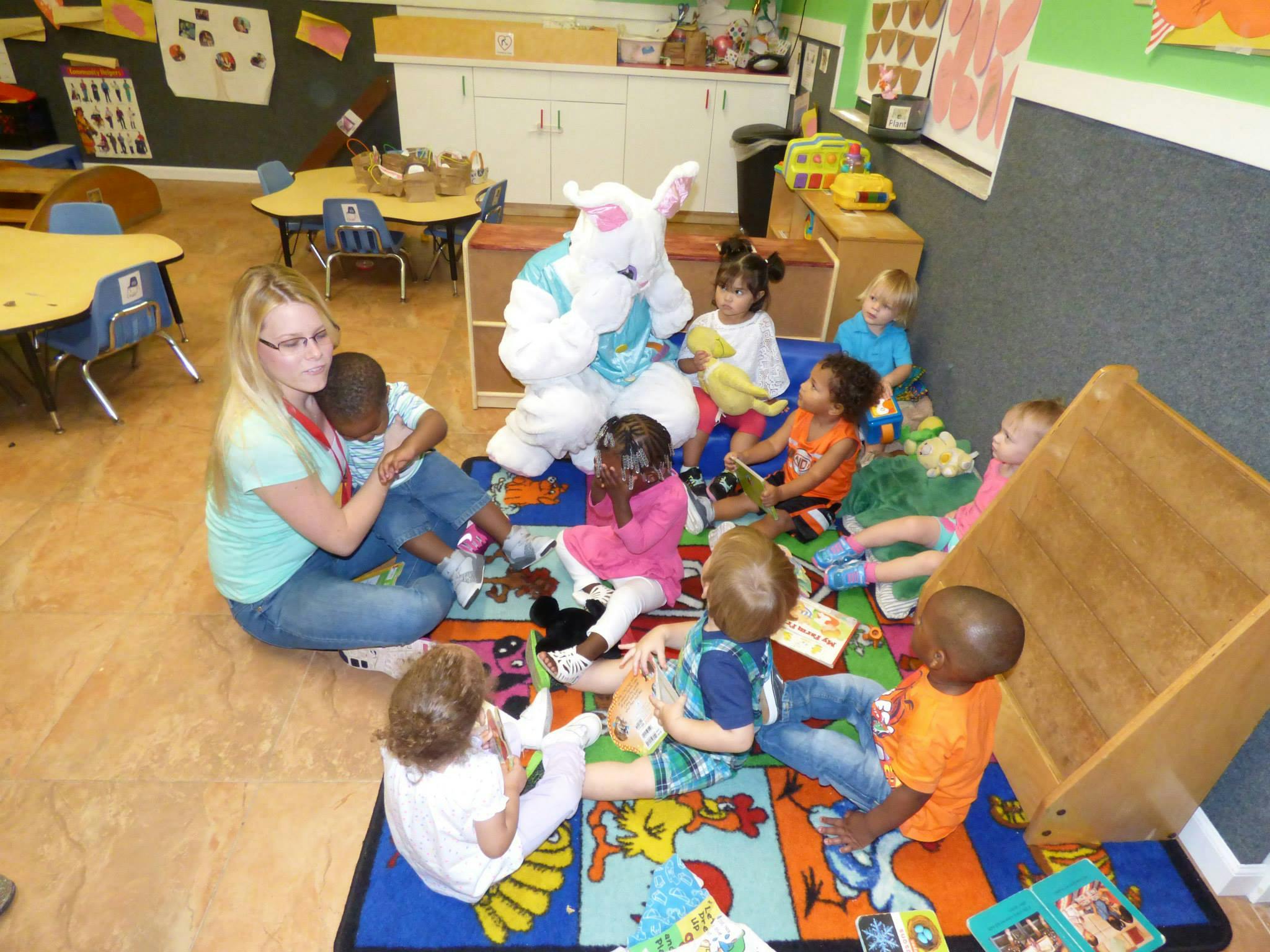 Person in bunny costume and adult with children in a classroom