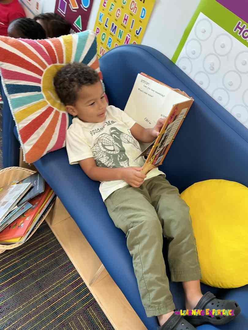 Child sitting on a blue chair reading a book