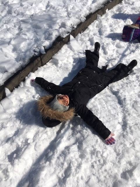 Child lying in the snow making a snow angel