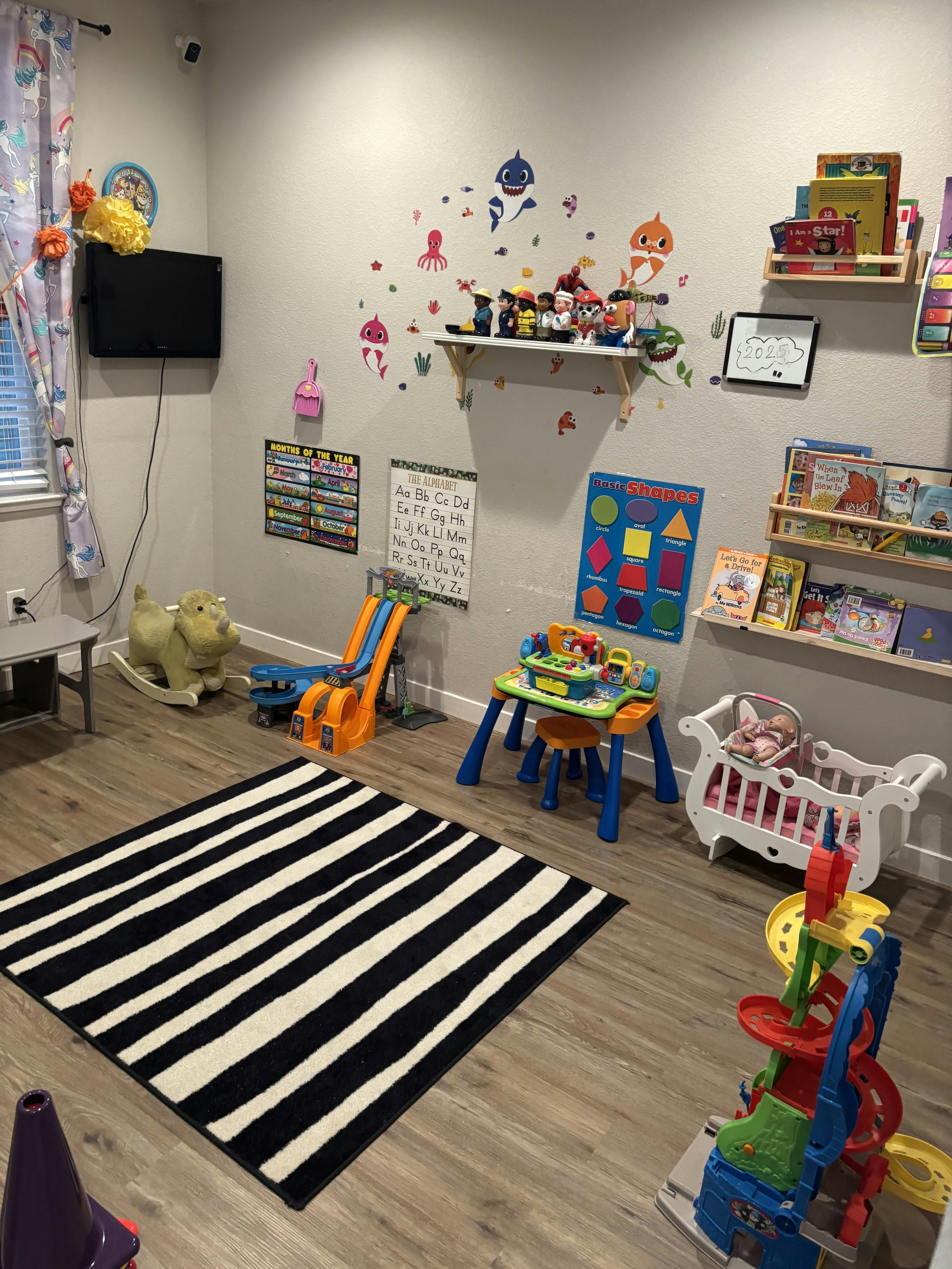 Children's playroom with toys, a black and white striped rug, and learning posters