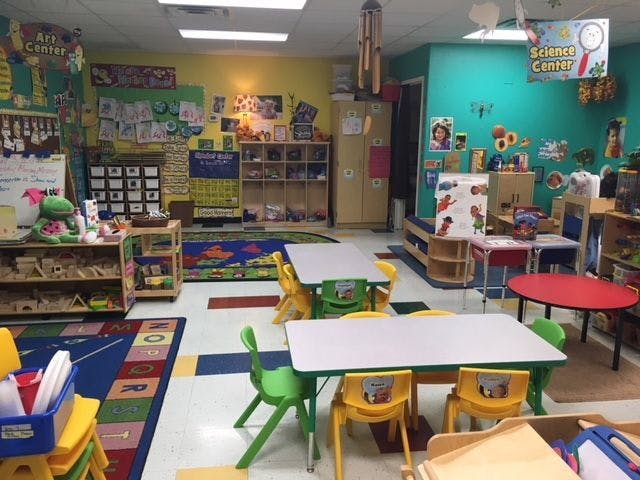 Classroom with small tables and chairs, shelves, and colorful decorations