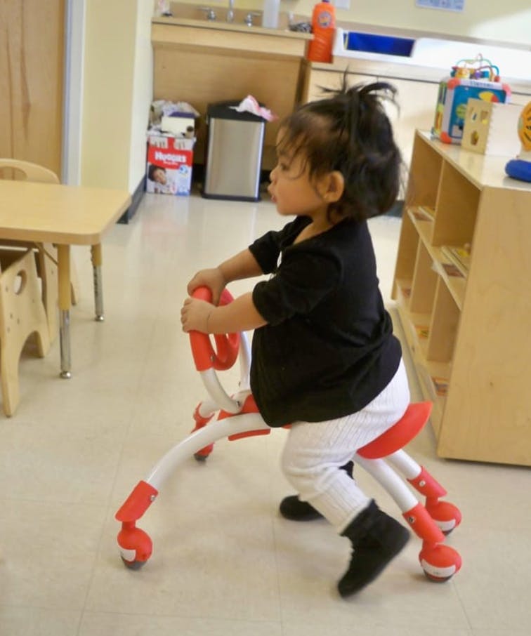 Child riding a red and white ride-on toy