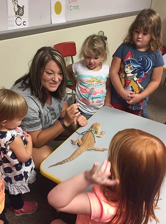 Adult and children gathered around a table with a lizard