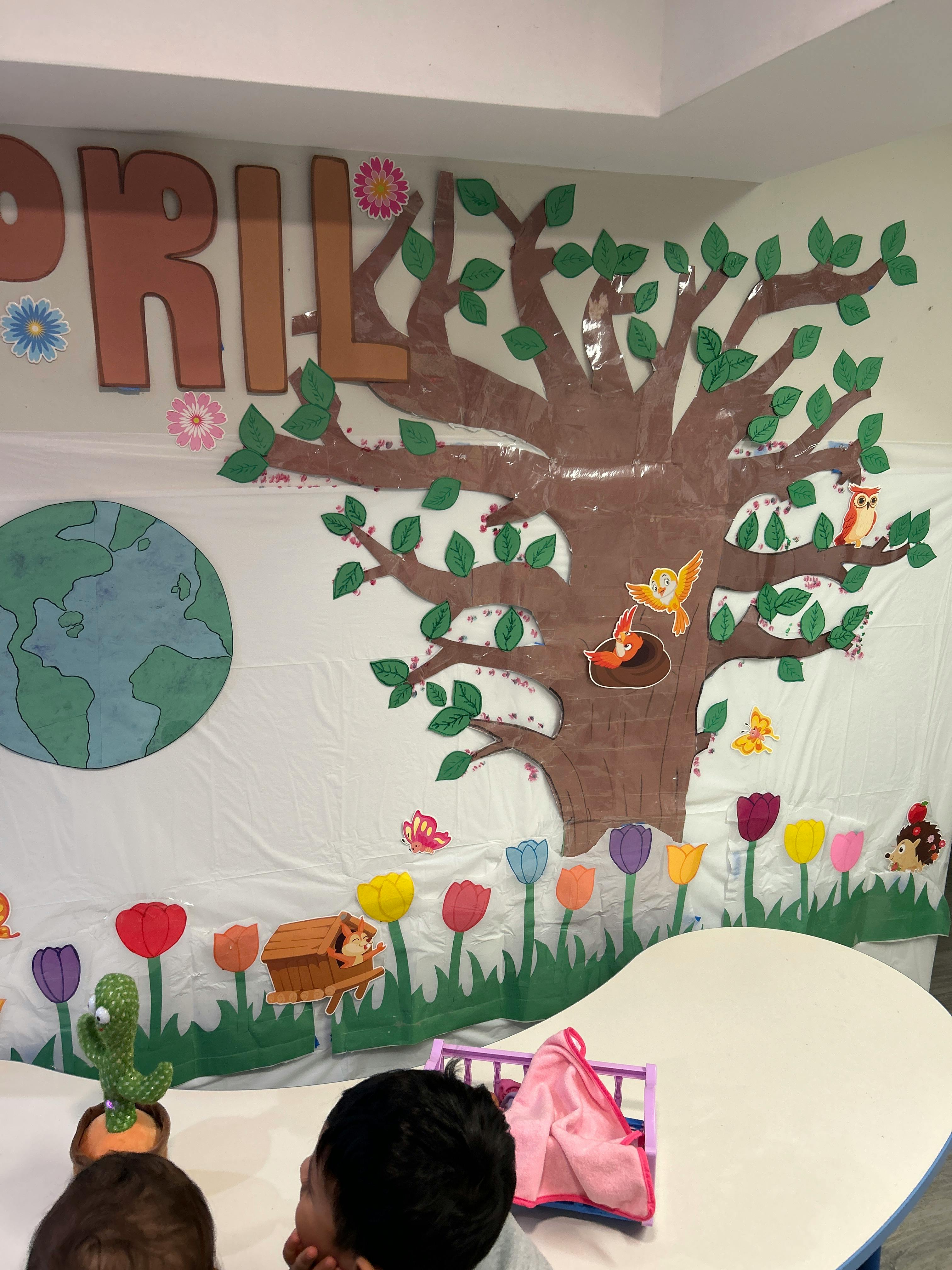 Classroom wall decorated with a tree, flowers, and the word "APRIL"