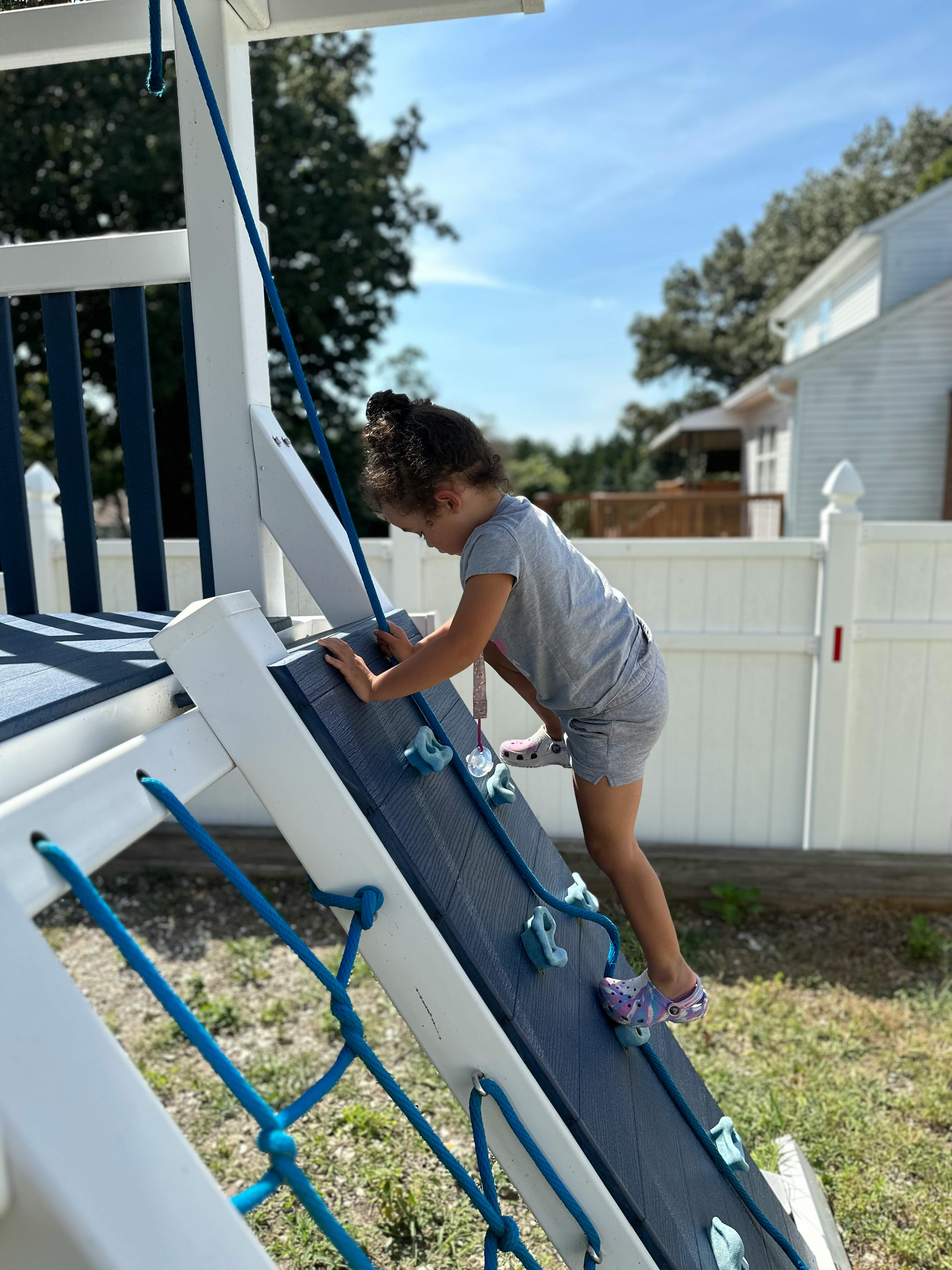 Child climbing a rock wall on a playset