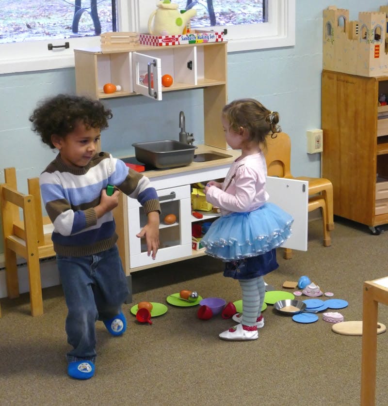 Two children playing with a toy kitchen set