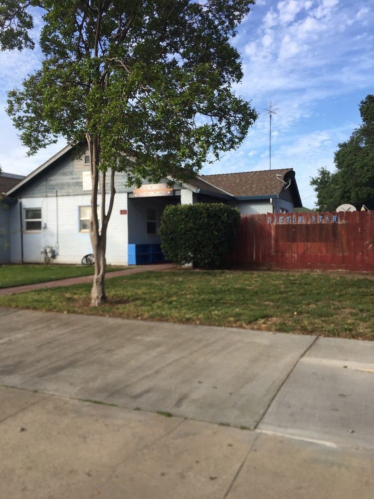 House with a tree in front and a red fence