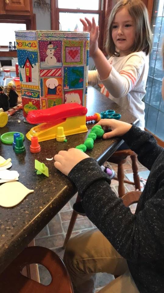 Child playing with playdough and toys on a counter