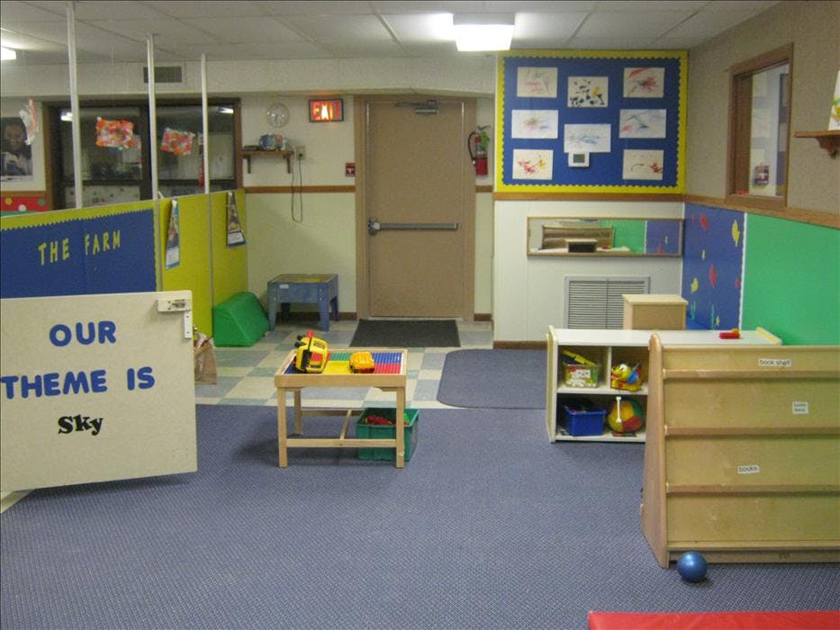 Playroom with small tables, storage units, and a sign that reads "OUR THEME IS Sky"