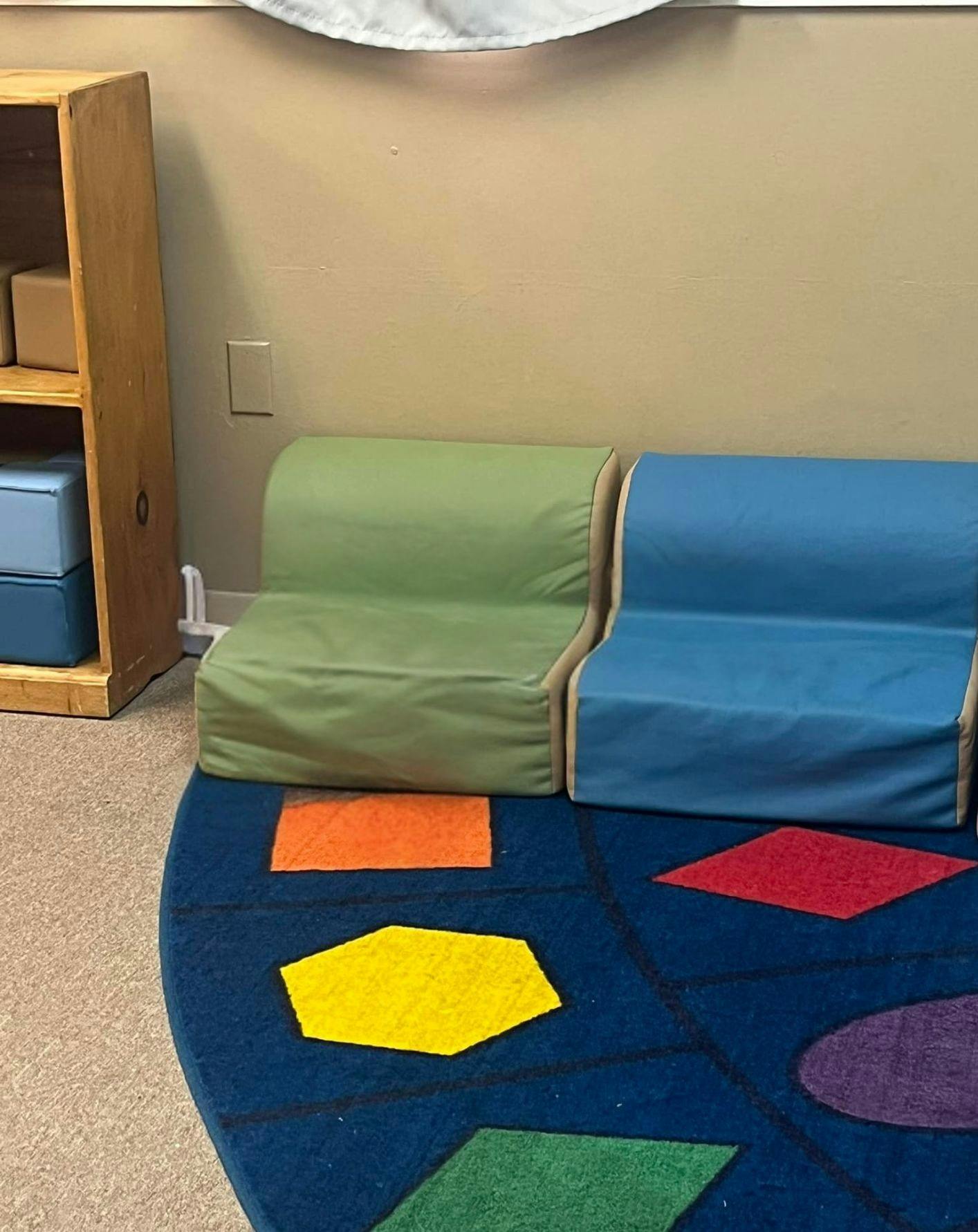 two small couches, one green and one blue, in a classroom