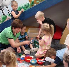 Adult and children playing with toys on the floor