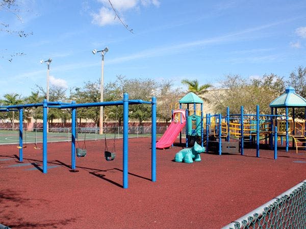 Playground with swings, slides, and climbing structures on a red surface
