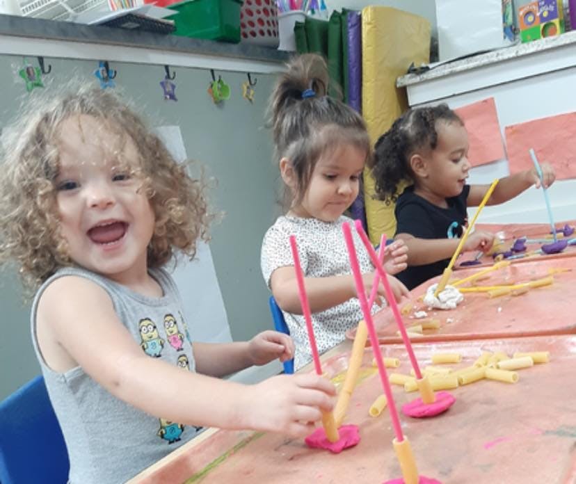 Three children playing with craft materials at a table