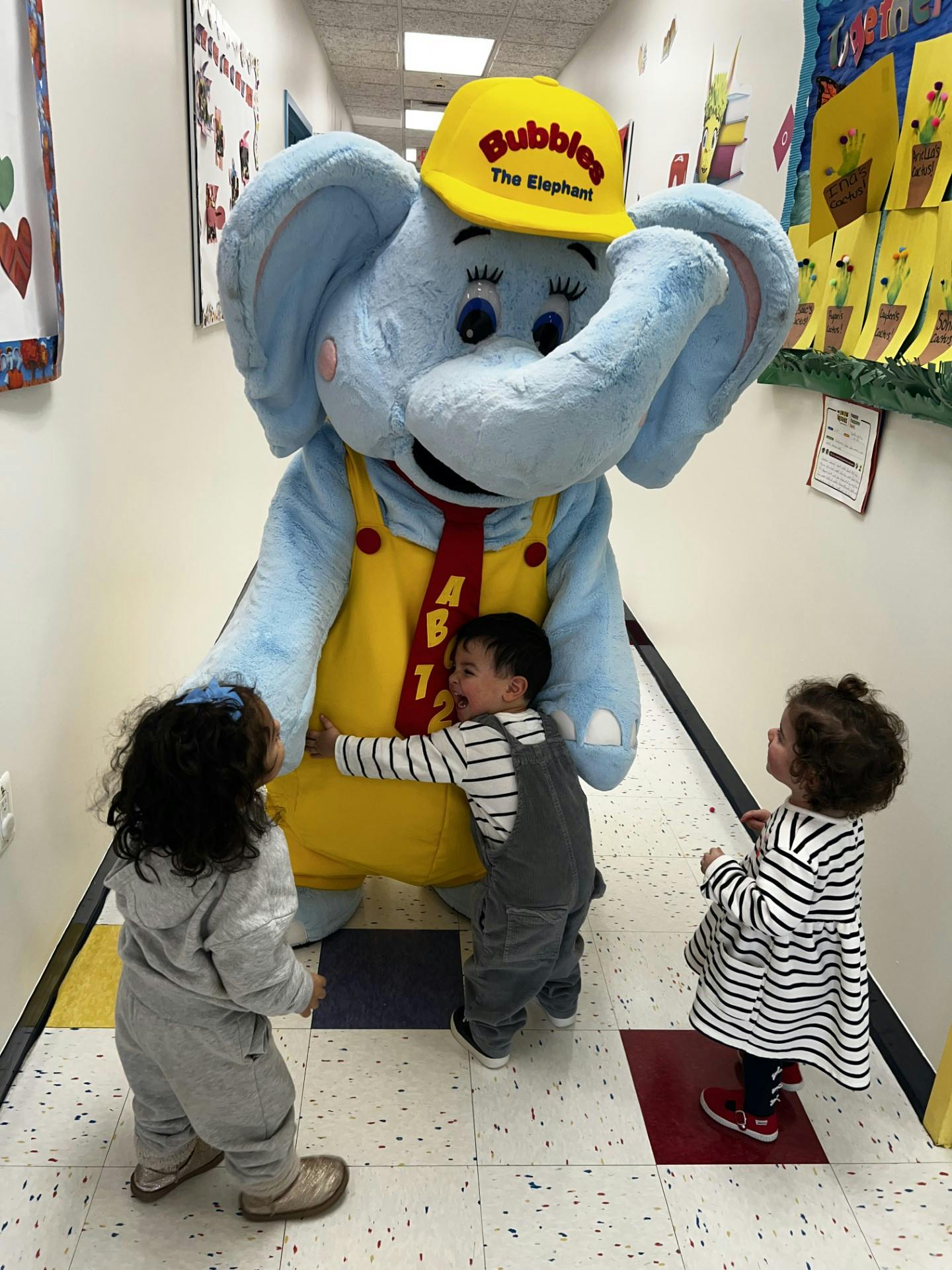 Mascot in elephant costume with "Bubbles The Elephant" hat interacting with children