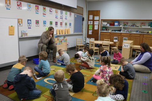 Adults and children sitting on a rug in a classroom