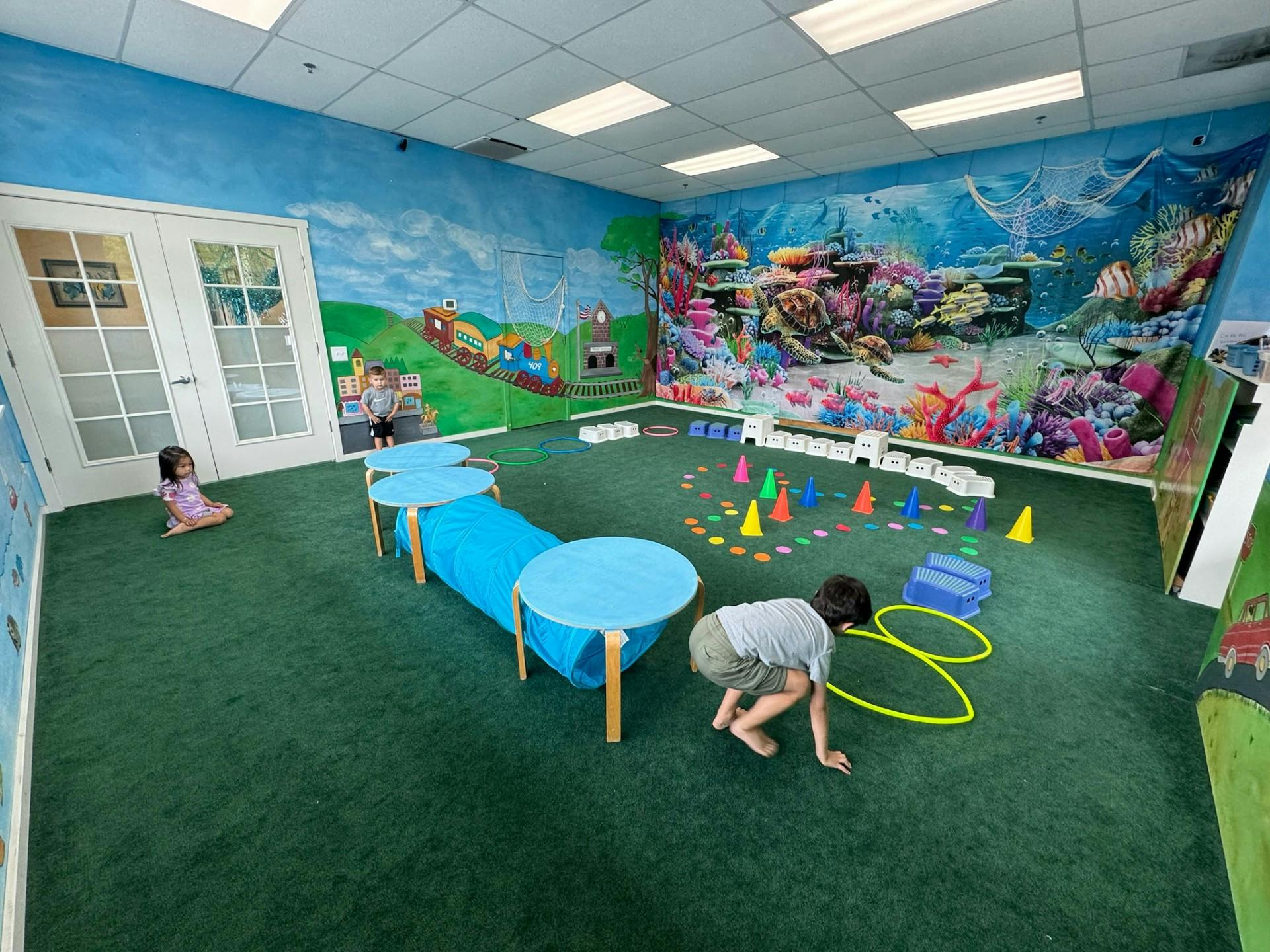 Two children playing in a room with colorful wall murals