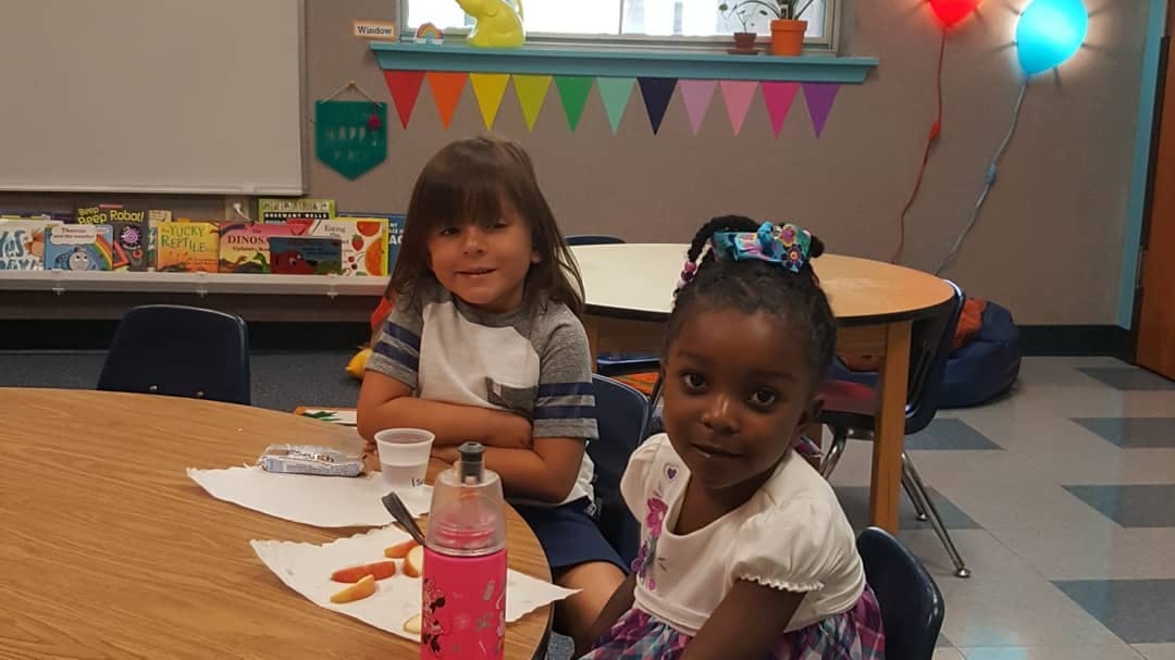 Two children sitting at a table in a classroom