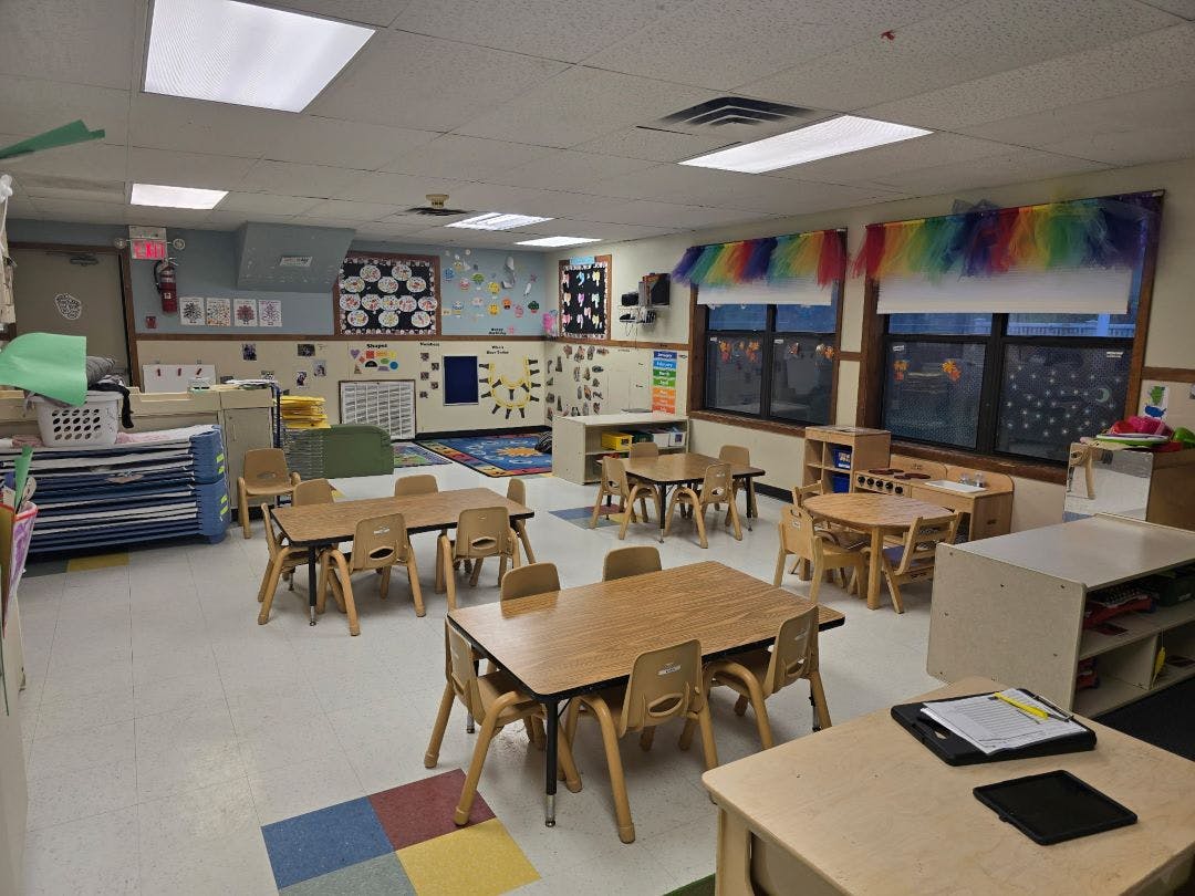 Empty preschool classroom with small tables and chairs