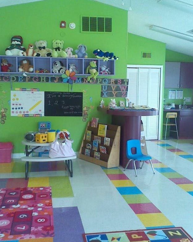 Classroom with green walls, colorful floor, and stuffed animals on shelves